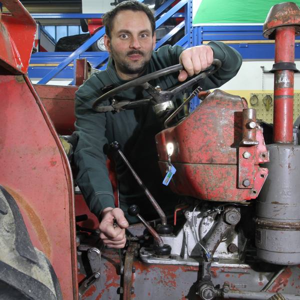 Reparatur an einem roten Oldtimer-Traktor